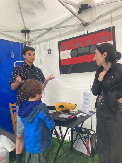 Two science communicators talking to one child in "The tape of life" stand.